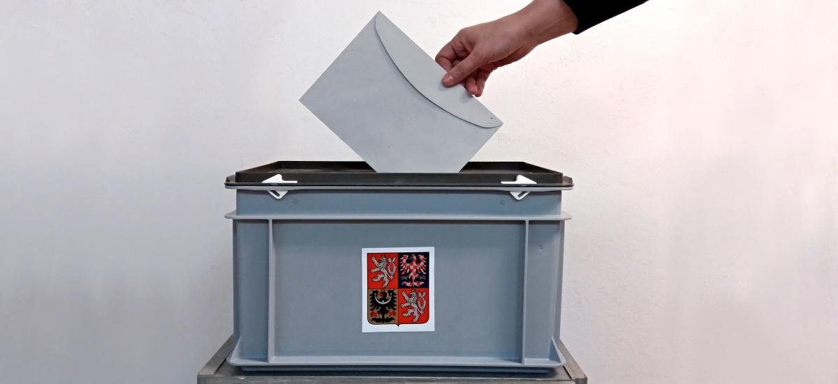 Ruka vkládající obálku do volební urny