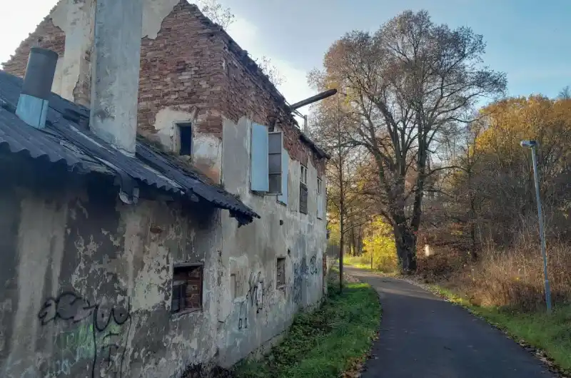 Fotografie budovy včetně nebezpečně vypadajícího střešního trámu.