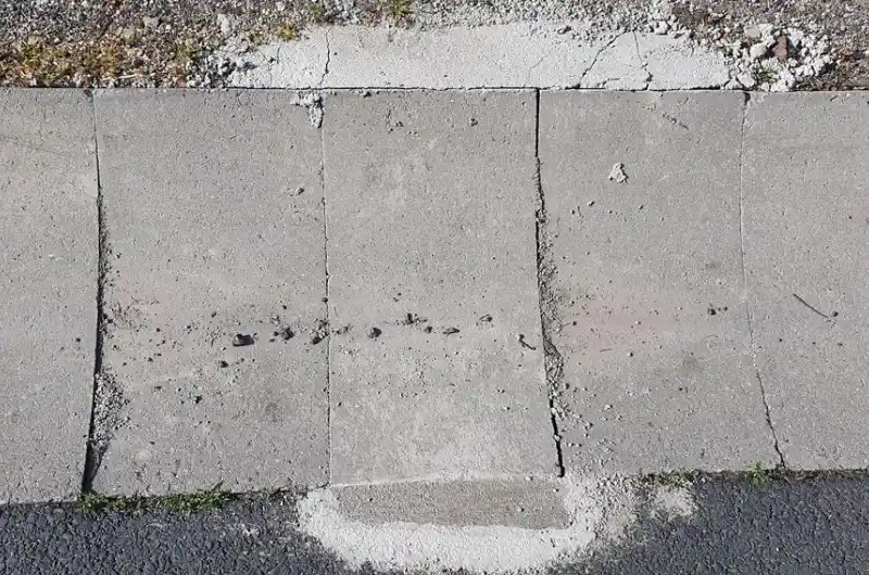 Nevzhledné nepravidelné příhozy betonu podél žalobovky, které se navíc loupu.