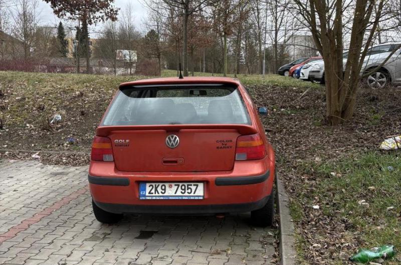 Červené auto dlouhodobě stojí na parkovacím místě bez pohybu.