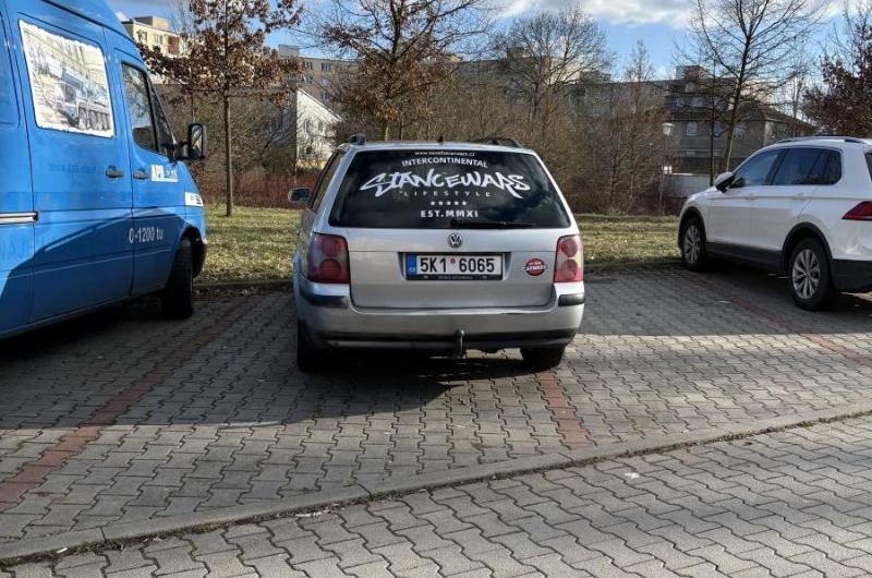 Stříbrné auto stojí šikmo a zabírá více parkovacích míst.