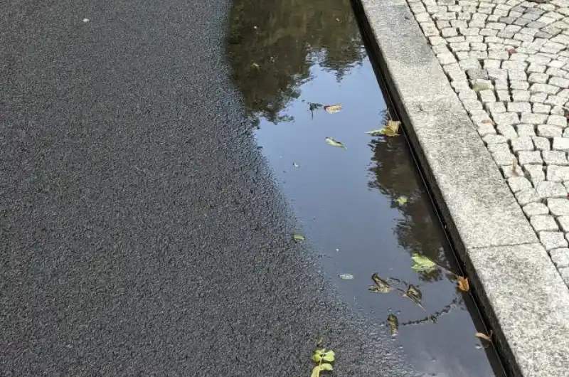 Louže a v pozadí dešťová vpusť