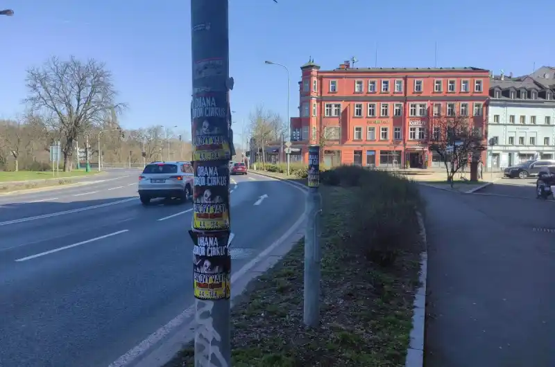 Černá reklama na cirkus umístěná na sloupu VO